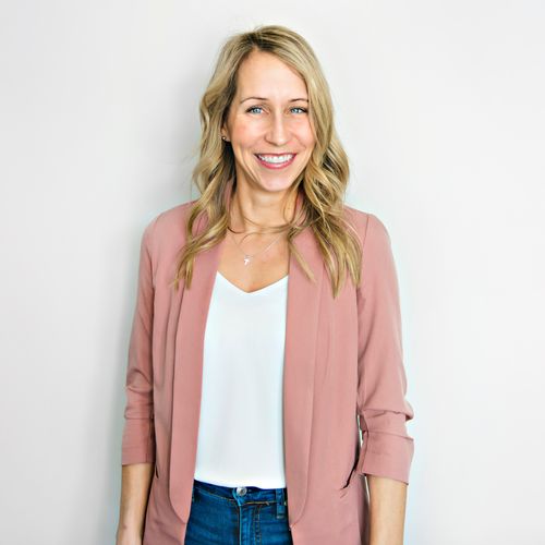 Smiling middle age woman wearing a pink blazer and a white shirt and jeans