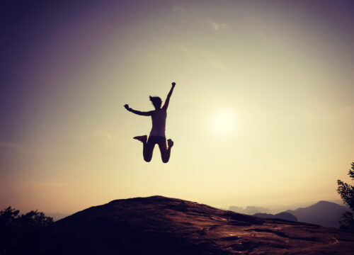 Woman jumping on a mountain hike